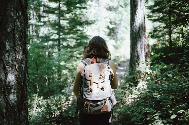 Chica en el bosque con una mochila hipster