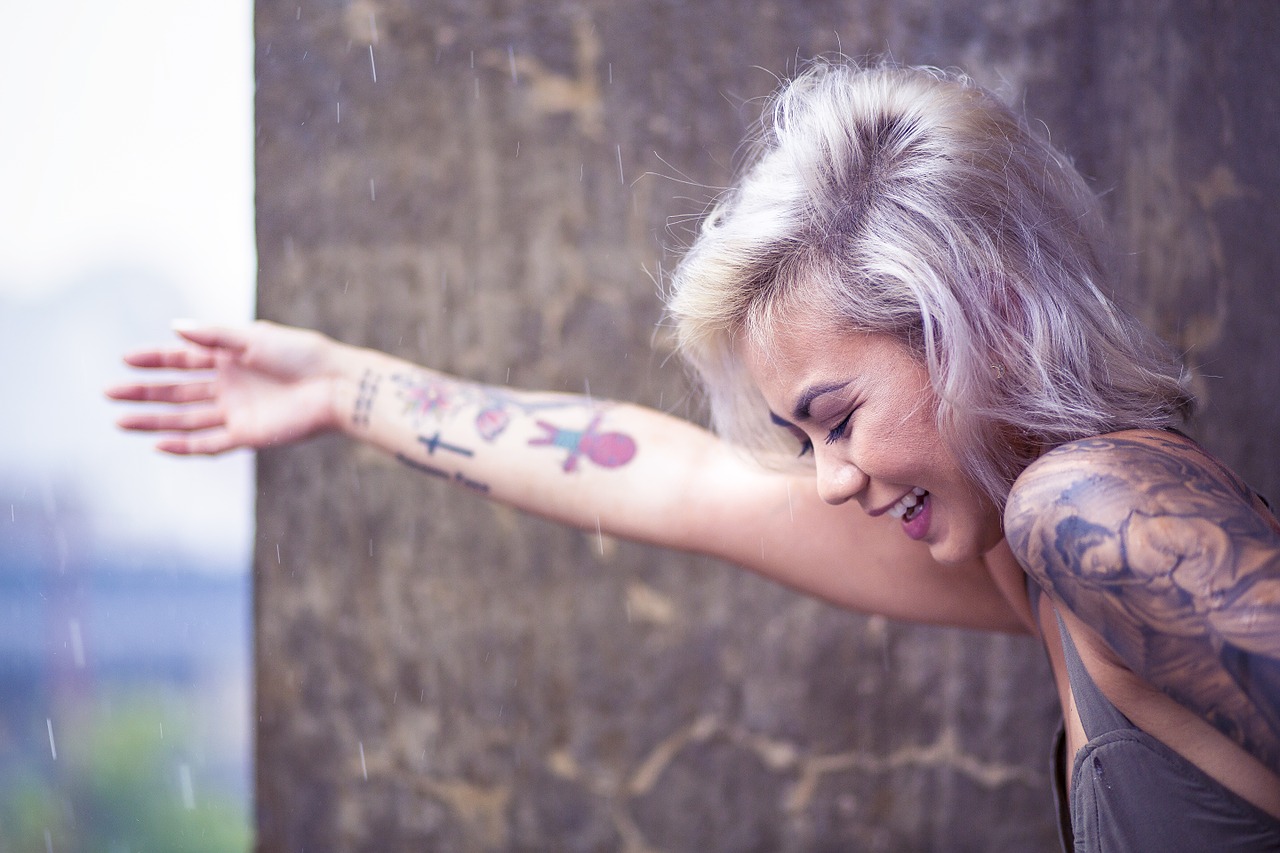 Chica hipster con tatuajes en los brazos.
